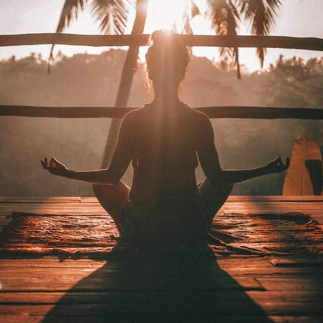 Donna seduta in meditazione al tramonto